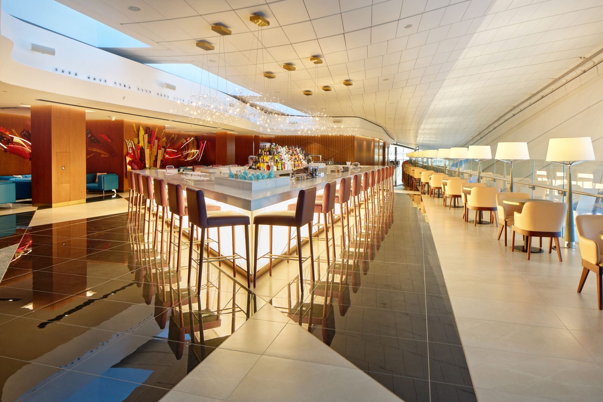 Completed Etihad lounge bar with backlit stone counter, sculptural glass artwork and dining seating