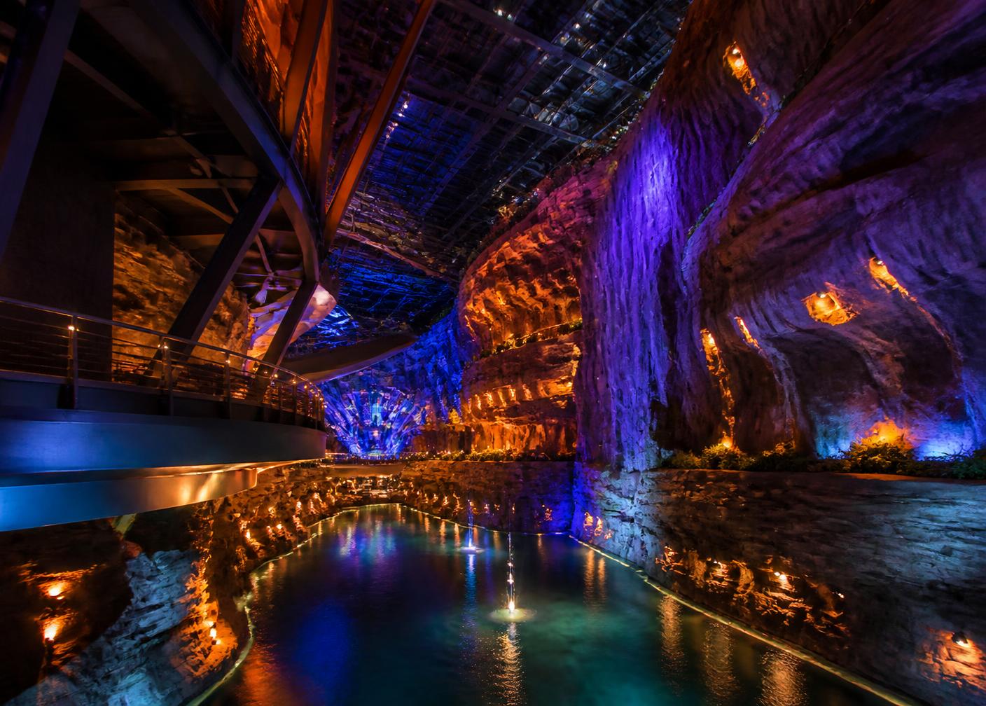Immersive themed entertainment interior with sculpted rockwork and coloured lighting